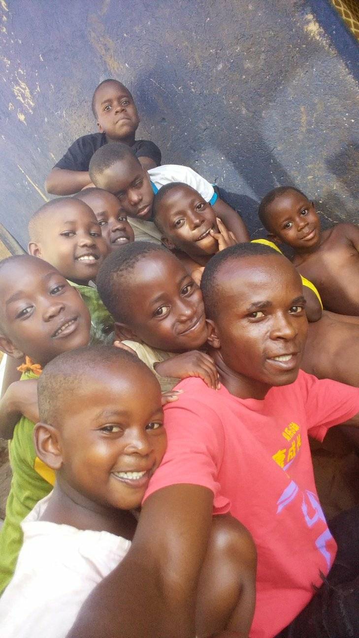 Bugingo "Desire" Moses with some of the children, their faces pressed close together and smiling